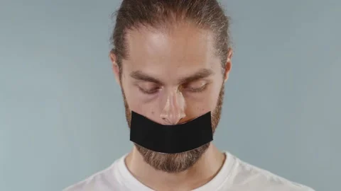 Close up face portrait man looking at camera serious and tearing tape from her Video stock 133639870