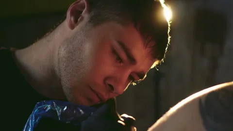 Close-up face portrait of working with covered needle machine tattoo artist. Stock Footage 170008316