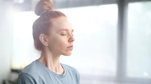 Close-up face of pretty redhead young woman doing breathing yogic practices at Stock Footage 133022018