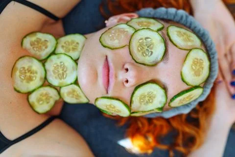 Close-up face red-haired young woman with round slices of cucumber, cucumber Stock Photos