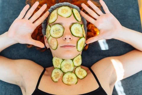 Close-up face red-haired young woman with round slices of cucumber, cucumbe.. Stock Photos