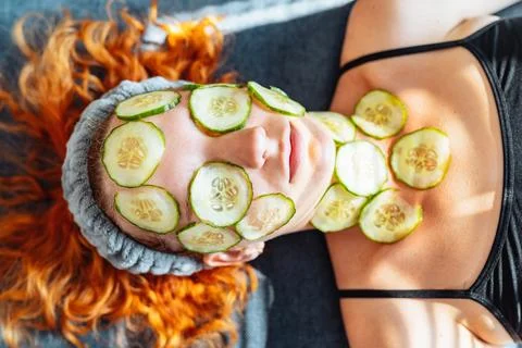 Close-up face red-haired young woman with round slices of cucumber, cucumber Stock Photos