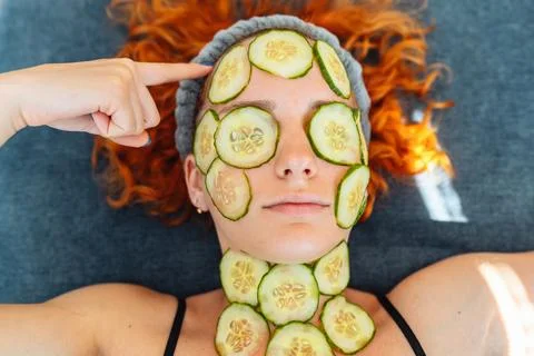Close-up face red-haired young woman with round slices of cucumber, cucumber Stock Photos