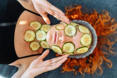 Close-up face red-haired young woman with round slices of cucumber, cucumber Stock Photos