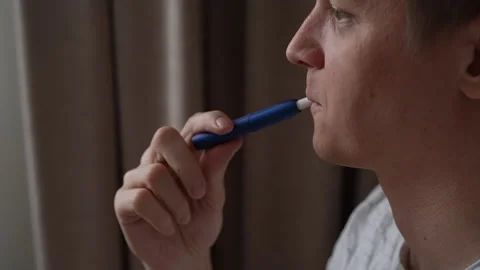 Close-up face of relaxed young man exhaling smoke from heated tobacco product Stock Footage 301394513
