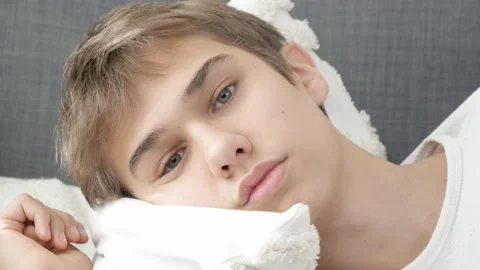 Close up face of sad looking pensive teen boy lying on sofa, bored at home alone Stock Footage 221424780