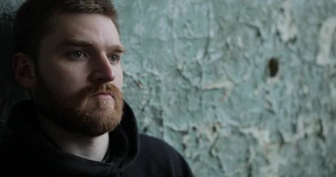 Close-up to the face of a sad man with a red beard who is feathers against an Stock Footage 126388399