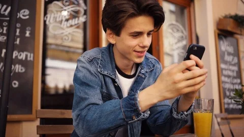 Close up face serious young boy sitting in cafe use phone drink juice portrait Stock Footage 92052704