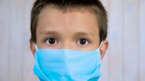 Close up of the face of a seven year old child wearing a blue medical mask and 動画素材 137380856