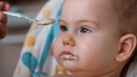 Close up of the face of a small child eating from a spoon Stock Footage 127702787