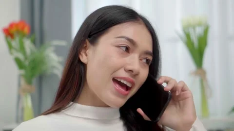 Close up face smiling face asian woman making phone call, working on laptop.. Stock Footage 244974569