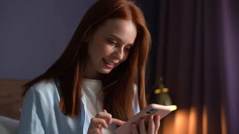 Close-up face of smiling red-haired young woman typing message on mobile phone 스톡 동영상 142789307