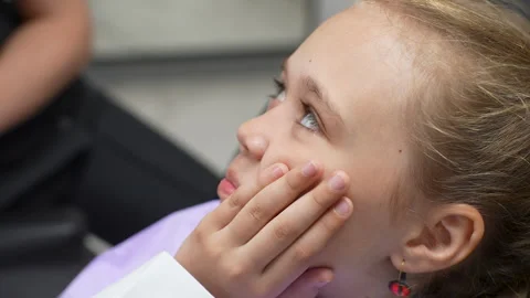 Close-up face of suffering from toothache cute little girl sitting in dentist Stock Footage 245416507