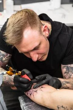 Close up of face of tattoo master making tattoo Stock Photos