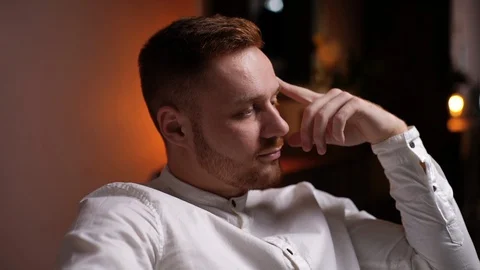 Close-up of face of thoughtful handsome young bearded man sitting in soft Stock Footage 128777356