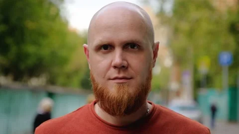 Close-up of the face of a young bald guy with a red beard looking at the camera. Stock Footage 139002028