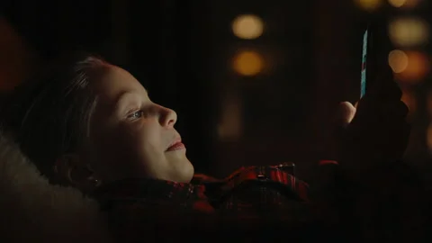 Close-up face of young girl using smartphone lying on bed in dark room Stock Footage 304873220