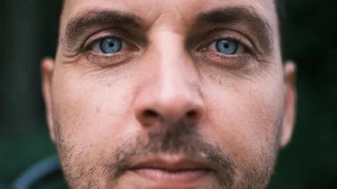 Close-up face of a young man with bright blue eyes looking seriously with Stock Footage 197786314