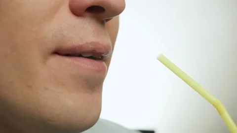 Close-up face of young man drinking through plastic cocktail tube Stock Footage 148241964