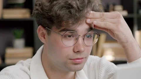 Close-up of the face of a young man with glasses typing and working on a Stock Footage 316094978