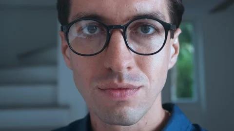 Close up face of young man in his 30s wearing glasses looking at camera and Video stock 228959414