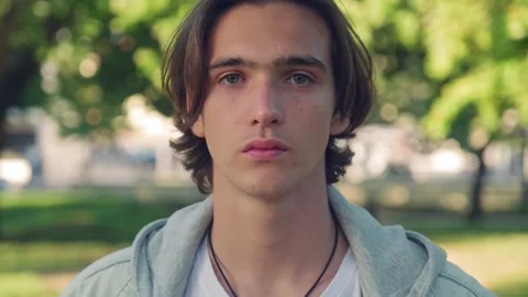 Close up face of an young man is looking to the camera,  in the park . Man wi Stock Footage 204156772