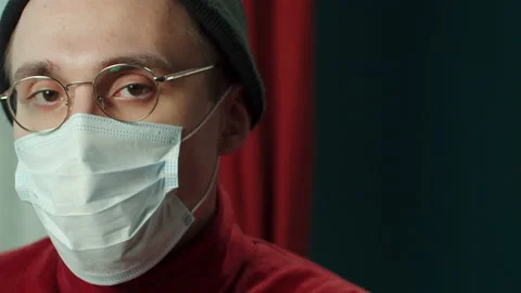 Close-up face of young man in protective mask, wearing glasses, hat. Headshot of Stock Footage 151331296