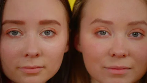 Close-up faces of identical twin sisters looking at camera. Slim beautiful young Stock Footage 162843397