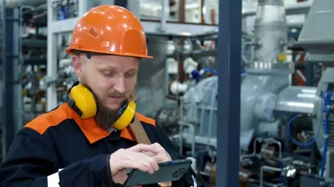 Close-up of a factory worker in a helmet, pulls out a smartphone to control a Stock Footage 167727113