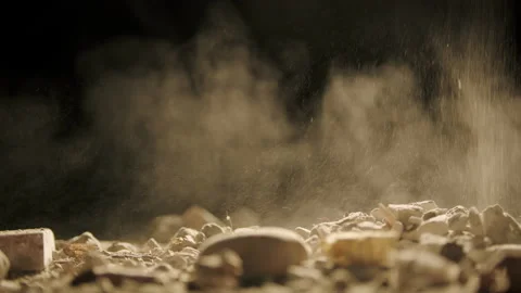 Close-up Falling dust and rocks on surface Black background backlit, slow Stock Footage 151933784