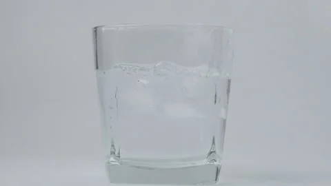 Close up of falling ice cubes in pure drinking water in glass on white backgroun Stock Footage 235971118