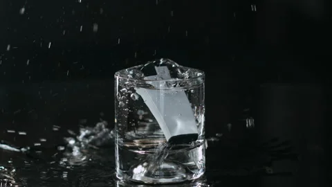 Close up of Falling Lighter and Coins into a Glass Full of Water, Splasing Stock Footage 147421445