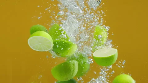 Close-up of falling ripe limes into the sparkling water on yellow background Stock-Footage 158678689