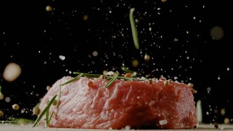 Close-up of falling salt and pepper on raw beef steaks on table, freeze motio Foto stock