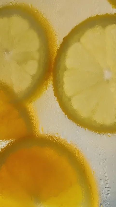 Close-up of falling sliced limes, oranges and lemons into the water on orange Stock Footage 316075224