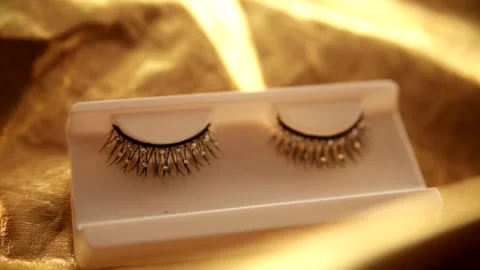 Close-up of false eyelashes. Beautiful fake eyelashes with rhinestones on gold Stock Footage 163818152