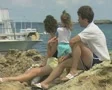 Close up of family sitting on rock looking at sea SD Footage