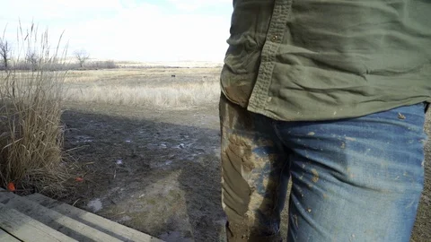 Close on farm worker’s muddy boots and pants Stock Footage 121089731