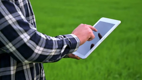 Close up of a Farmer man read or analysis a report in tablet computer on a green Video stock 194744609