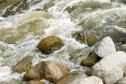 Close up fast flowing water between rocks in the mountain Stock Photos