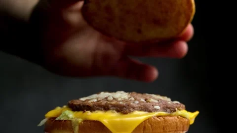 Close up of fast food burger being intentionally spoiled by cook spit. Stock Footage 323012313