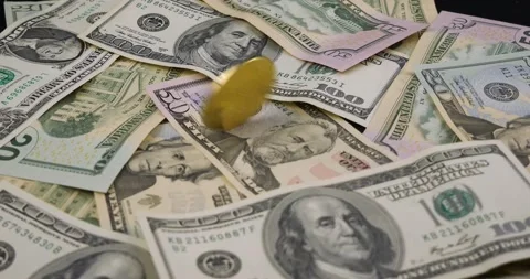 Close-up. Fast rotation of a bitcoin coin on scattered dollar bills. Gold Stock Footage 232337328