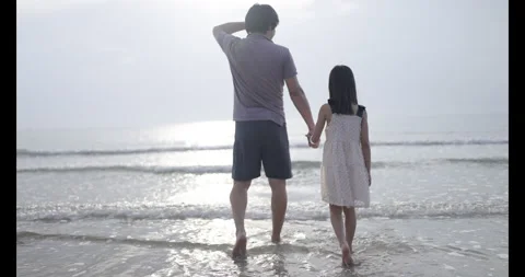 Close up of a father daughter holding hands walking together by the ocean Stock Footage 342854331