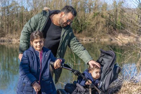 Close-up of father with stroller and two children walking along the Aare rive Stock Photos