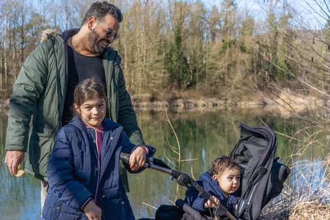 Close-up of father with stroller and two children walking along the Aare rive Stock Photos