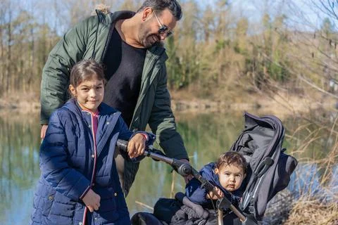 Close-up of father with stroller and two children walking along the Aare rive Stock Photos