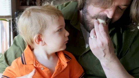 Close up of a father teaching his son how to eat a banana Stock Footage 75658625