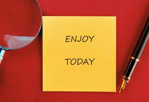 Close-up features a yellow sticky note with the phrase ENJOY TODAY, a magnifying Fotos de archivo