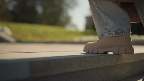 Close up of feet in beige boots walking down stone steps with sunlight and Stock Footage 346653559
