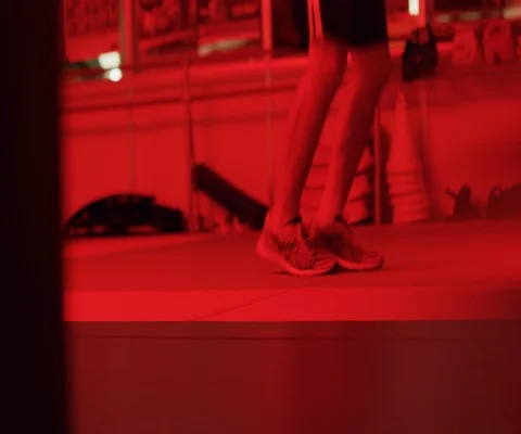 Close up of feet jumping over skipping rope in gym in red light Stock Footage 147042780